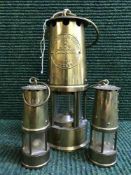 An Eccles Protector miner's lamp and two miniature brass miner's lamps