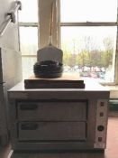 A stainless steel counter top pizza oven with pizza trays