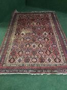 A fringed woolen Persian style rug on red ground