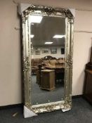 A large bevelled mirror in ornate silvered frame