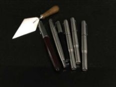 A silver miniature trowel and a collection of assorted pens