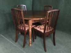 A circular oak pull out table and four inlaid mahogany rail backed chairs