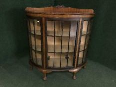 An early twentieth century mahogany bow fronted display cabinet on ball and claw feet