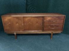 A mid twentieth century teak sliding door sideboard fitted with four drawers