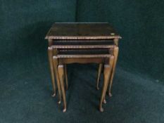 A nest of three walnut glass topped tables