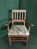An antique pine kitchen armchair with tapestry seat