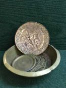 A large circular brass bowl containing copper and brass wall plaques
