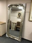 A large bevelled mirror in ornate silvered frame