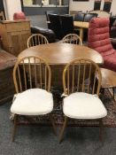 An Ercol light elm flap-sided dining table together with four Windsor chairs