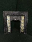 An antique cast iron fire insert with tiles