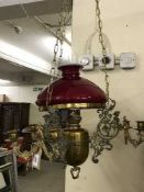 An antique brass hanging oil lamp with chimney and shade