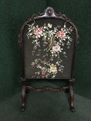 A late Victorian needlework fire screen in carved mahogany frame