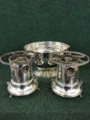 A large plated punch bowl and two plated food warmers on stands