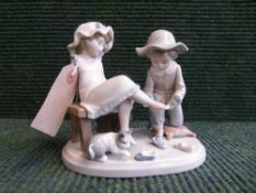 A Lladro figure - Boy and Girl trying on shoes