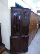 A mahogany double door corner display cabinet