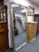 A tall silvered ornate bevelled mirror
