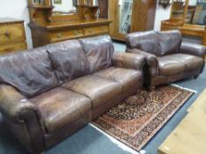 A brown leather three seater settee together with matching two seater settee