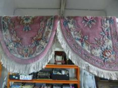 A pink fringed oval rug together with a D-shaped rug