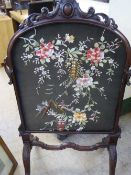 A Victorian needlework panel in heavily carved mahogany frame