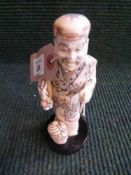 A carved resin figure on stand - Oriental gentleman with basket