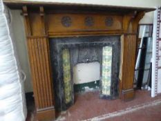 An early twentieth century carved oak fire surround with cast iron tiled insert