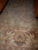 A floral woollen carpet on green ground