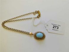 A gold pendant with turquoise coloured stone,