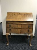 A bowfronted walnut bureau with tooled leather interior