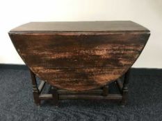 An antique oak drop leaf table fitted with a drawer
