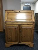 A pine writing bureau fitted with tooled leather interior and cupboard beneath