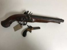 A replica double-barrel flintlock pistol and a miniture percussion pistol