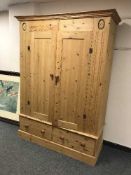 A pine double door wardrobe fitted with two drawers below