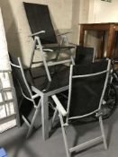 A metal glass topped garden table together with a set of four folding chairs