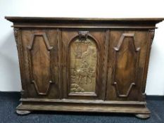 A Continental oak sideboard with carved panel depicting Gentleman on horse