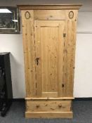 A pine single door wardrobe fitted with a drawer