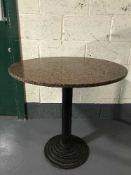 A circular marble topped pedestal cafe table