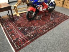 A fringed Persian Kashgai carpet on red ground