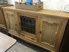 A continental oak triple door sideboard with leaded glass panel
