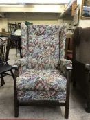A wing backed armchair upholstered in floral buttoned fabric