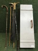 A painted wooden crate together with a vintage parasol and three walking canes one mounted in