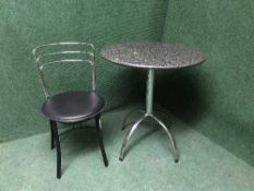 A circular marble pedestal cafe style table and chair
