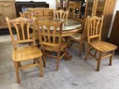 A circular pine pedestal dining table with plate glass top and six chairs