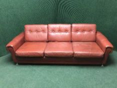 A red buttoned leather three seater settee with matching armchair