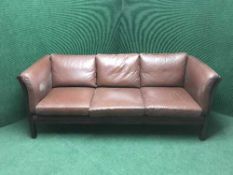 A wood framed brown leather three seater settee together with matching two seater settee