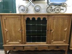 A continental oak triple door sideboard with leaded glass panel