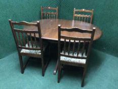 A circular oak pedestal extending table and four chairs