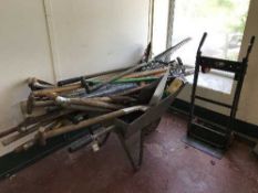 A wheelbarrow containing a large quantity of garden tools together with a black and decker light