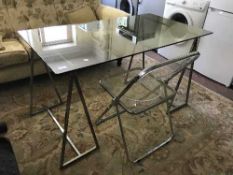 A contemporary glass topped desk together with folding metal and plastic chair