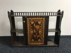 An antique mahogany wall cabinet with poker work panel door