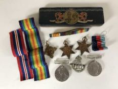 A tin of four WW II medals, some with ribbons, cap badge.
